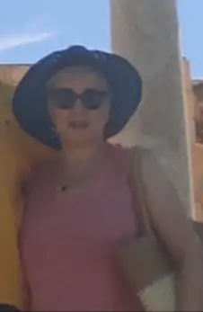 Valerie Millet Una persona con gafas de sol y un sombrero de ala ancha se encuentra al aire libre, sosteniendo una bolsa al hombro. Están vestidos con una blusa sin mangas y parecen estar en un lugar iluminado por el sol, muy parecido a lo que Valerie describió en su testimonio sobre las aventuras de verano. Bienestar Holistico