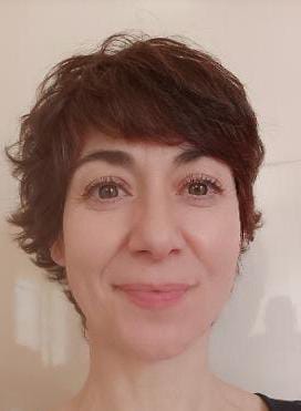Valerie Millet Una persona con cabello corto y ondulado y una leve sonrisa en el rostro, mirando directamente a la cámara. Bienestar Holistico