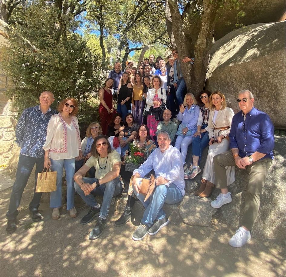 Valerie Millet Un grupo de personas posando juntas al aire libre, rodeadas de árboles y rocas durante un retiro empoderador. Algunos están sentados mientras otros están de pie, todos sonriendo a la cámara. Bienestar Holistico
